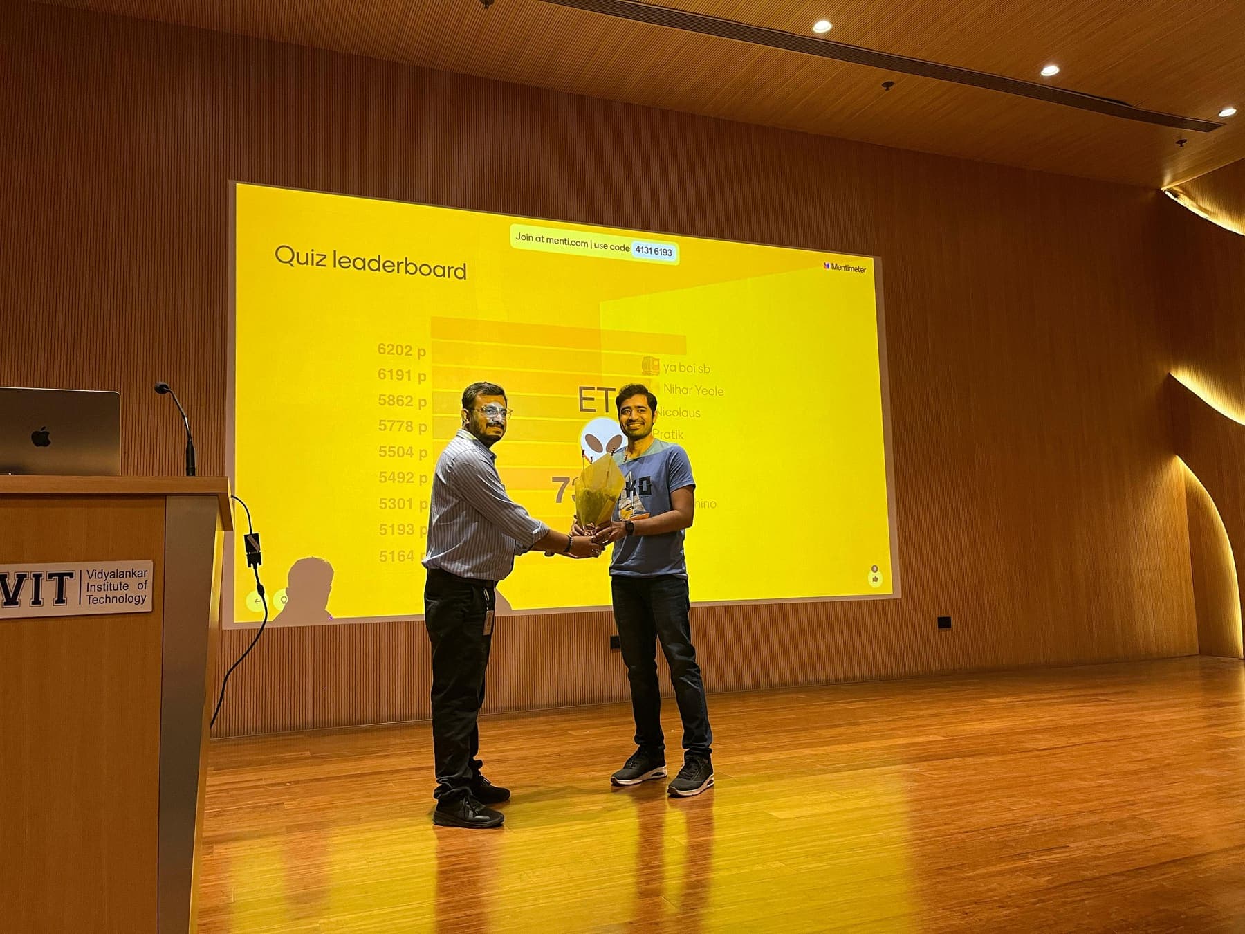 Quiz prize at the VIT conference. A quiz winner is handed a bouquet on stage at Vidyalankar Institute of Technology.